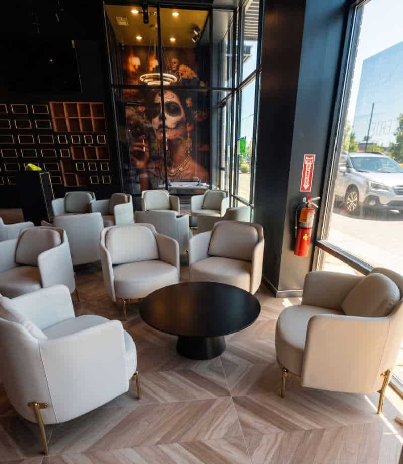 Interior of the Caballeros cigar lounge with cream armchairs, herringbone wood floor, personal cigar lockers, and a feature mural